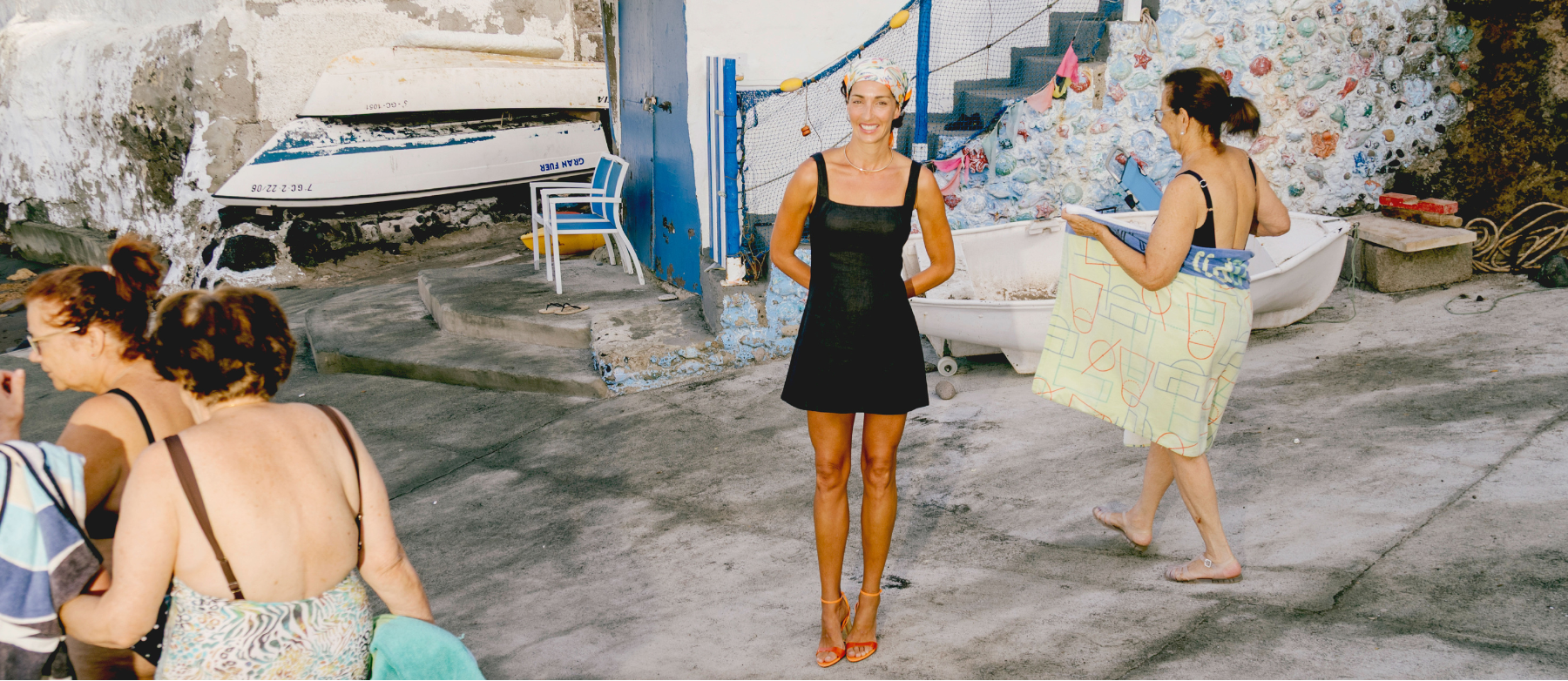Group of women standing on a street with a boat and building in the background